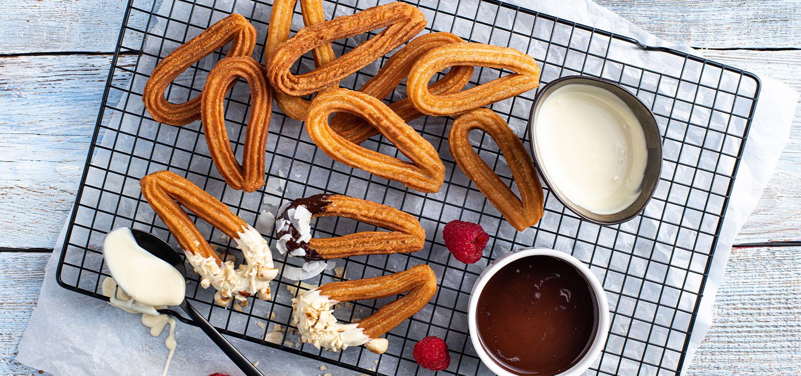 Churros valge ja tumeda (64%) šokolaadikastmega serveeritud hakitud sarapuupähklite ja kookoshelvetega